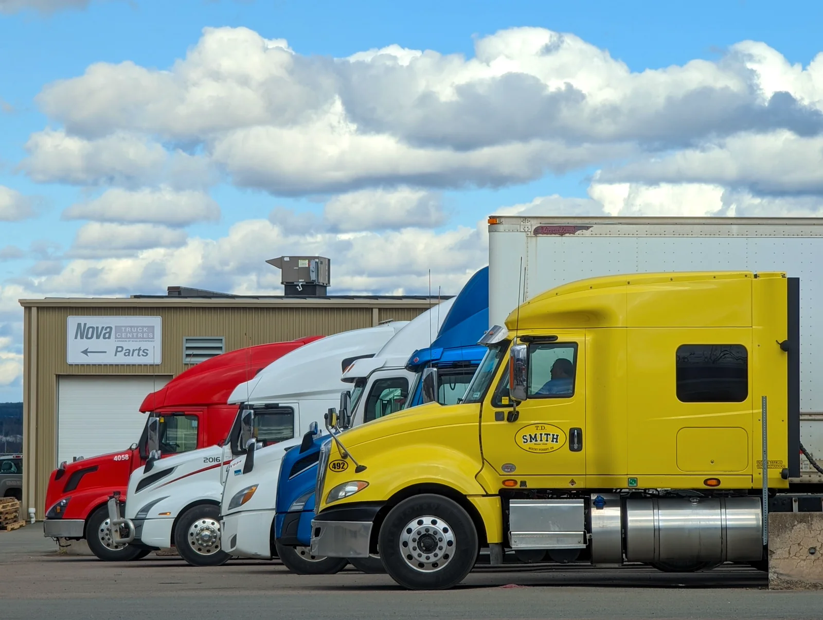 Semi trucks parked together in a commercial yard